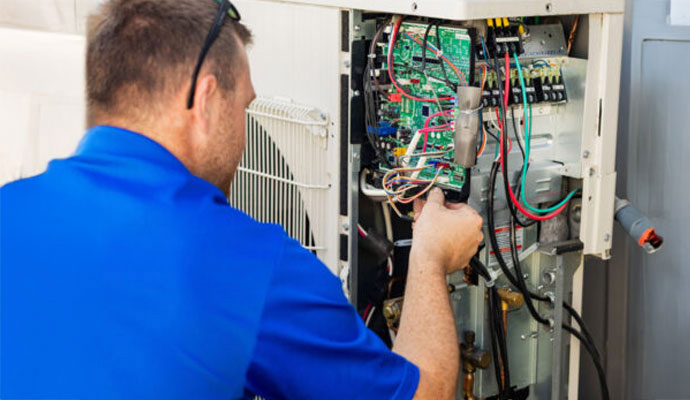 A HVAC technician of Handyside Plumbing, HVAC & Electrical repairing outdoor AC unit control board