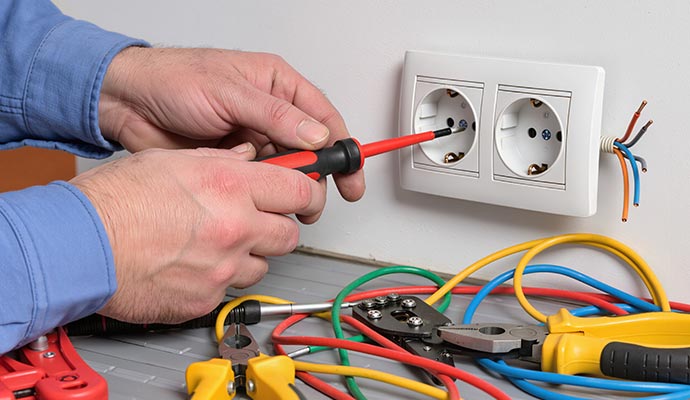 An electrician installing a new wall outlet with professional hand tools