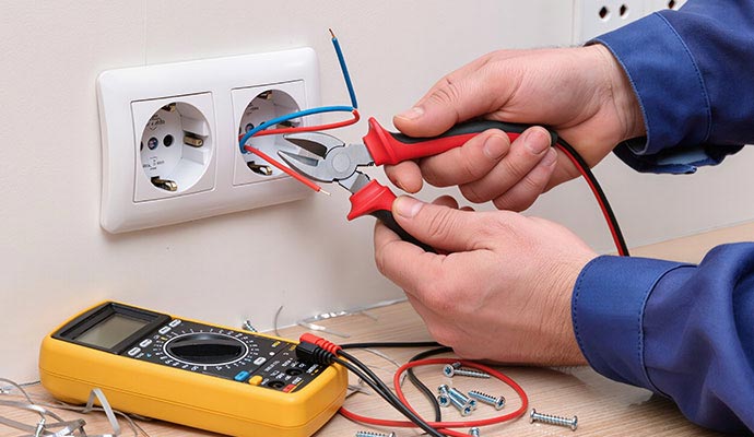 Electrician repairing a wall power outlet.