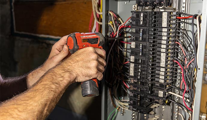 Electrician installing circuit breakers and panel services.