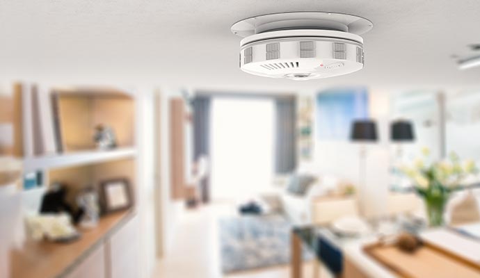 Modern smart smoke detector on home ceiling.