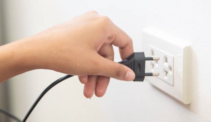 Person with wet hand plugging into outlet.