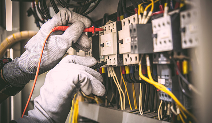 Electrician testing complex circuit wiring in a panel.