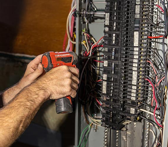 Technician opening breaker panel switch with equipment.
