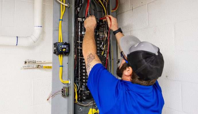 Electrician repairing a circuit breaker panel on a ladder