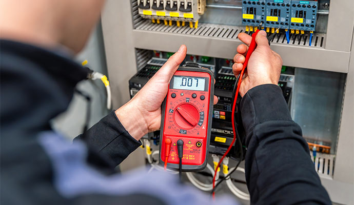 Electrician testing electrical panel with a digital multimeter