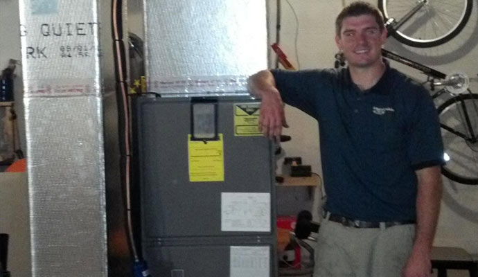 Handyside technician standing beside an installed residential oil furnace