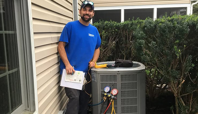 Handyside technician checking pressure and servicing outdoor heat pump system