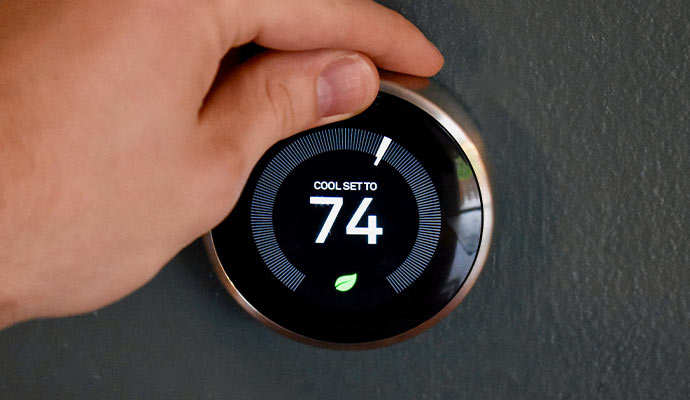 Hand adjusting a smart thermostat dial.