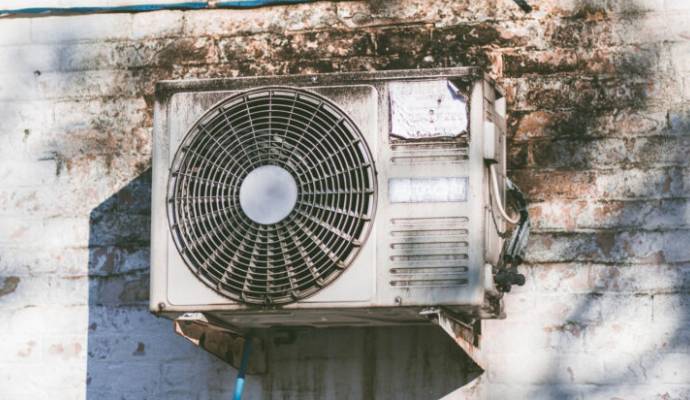 Old outdoor air conditioning unit on wall.