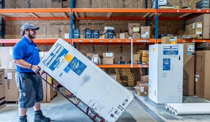 Professional technician moving a new Bradford water heater.