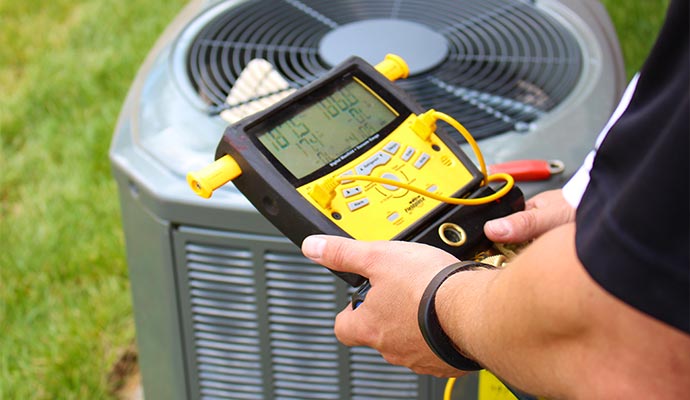 Technician using digital manifold gauge on AC unit