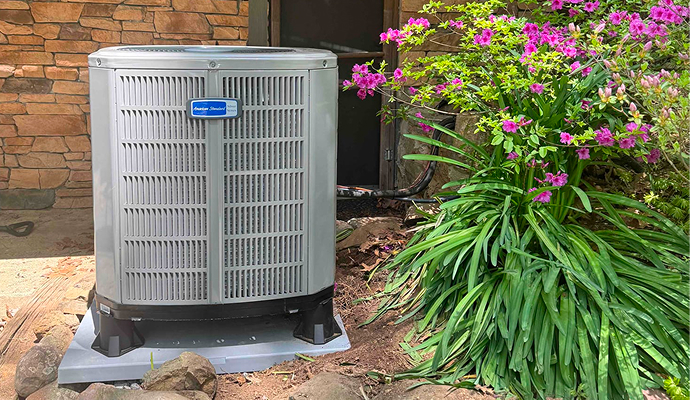 Installed American Standard outdoor heat pump unit beside a home