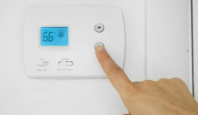 Person using wall mounted thermostat
