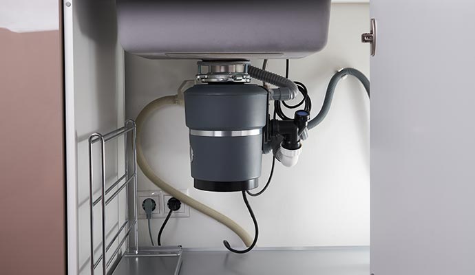 A kitchen garbage disposal unit installed under a sink.