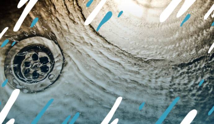 Close-up of a clean stainless steel kitchen sink drain with water ripple effec