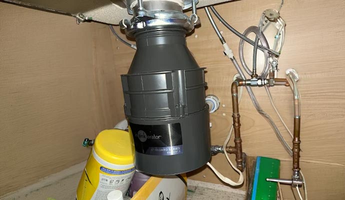 An InSinkErator Badger garbage disposal installed under a kitchen sink.