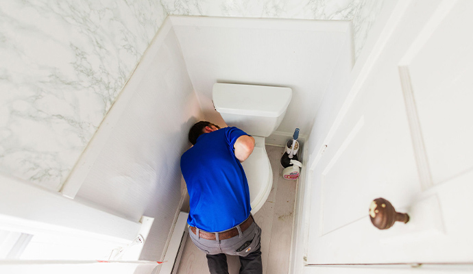 Plumber repairing toilet in bathroom