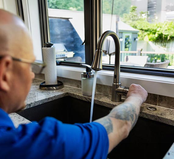 Professional plumber testing a new kitchen faucet.
