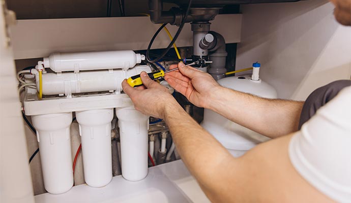 Technician installing a reverse osmosis water filtration system.