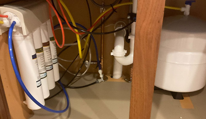 Reverse osmosis filter system with canisters and storage tank under a sink