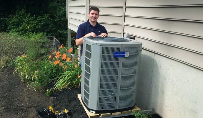 Professional technician standing with HVAC outdoor unit.
