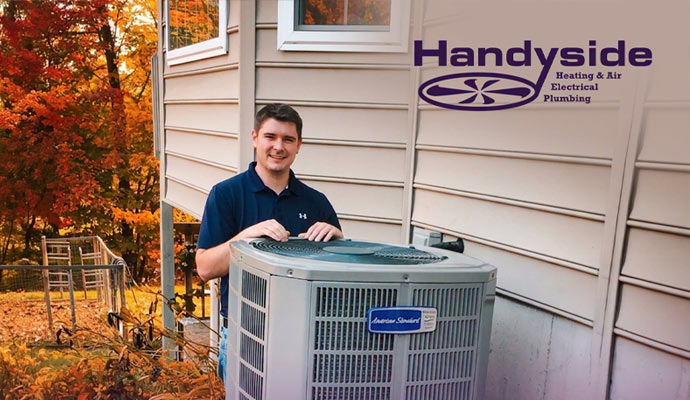 Technician standing beside an installed American Standard heat pump unit